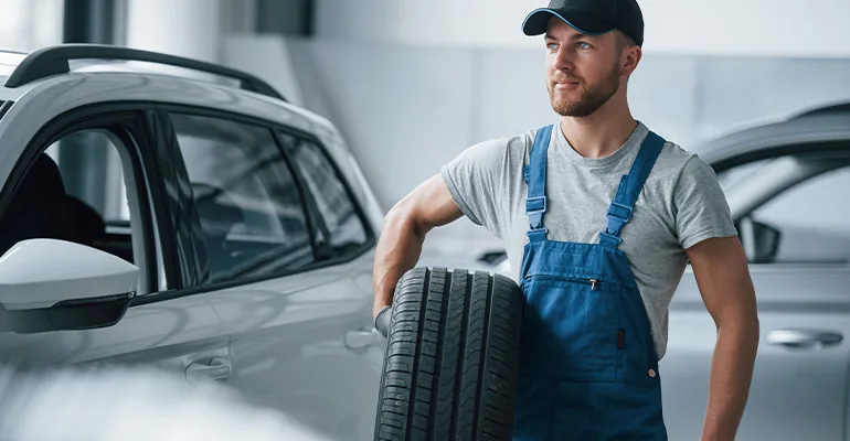 Technician inspecting a car tyre before summer driving in Abu Dhabi