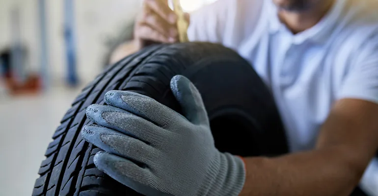Mechanic checking the manufacturing date and condition of a tyre in Abu Dhabi
